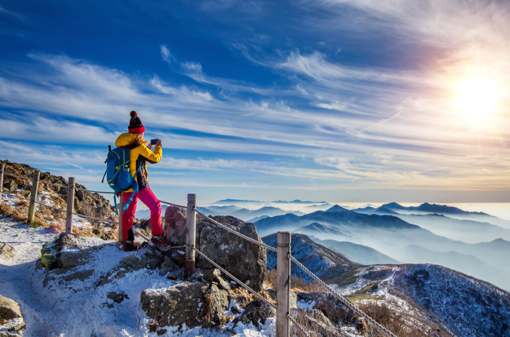Young woman hiker taking photo with smartphone on mountains peak treks , trekking